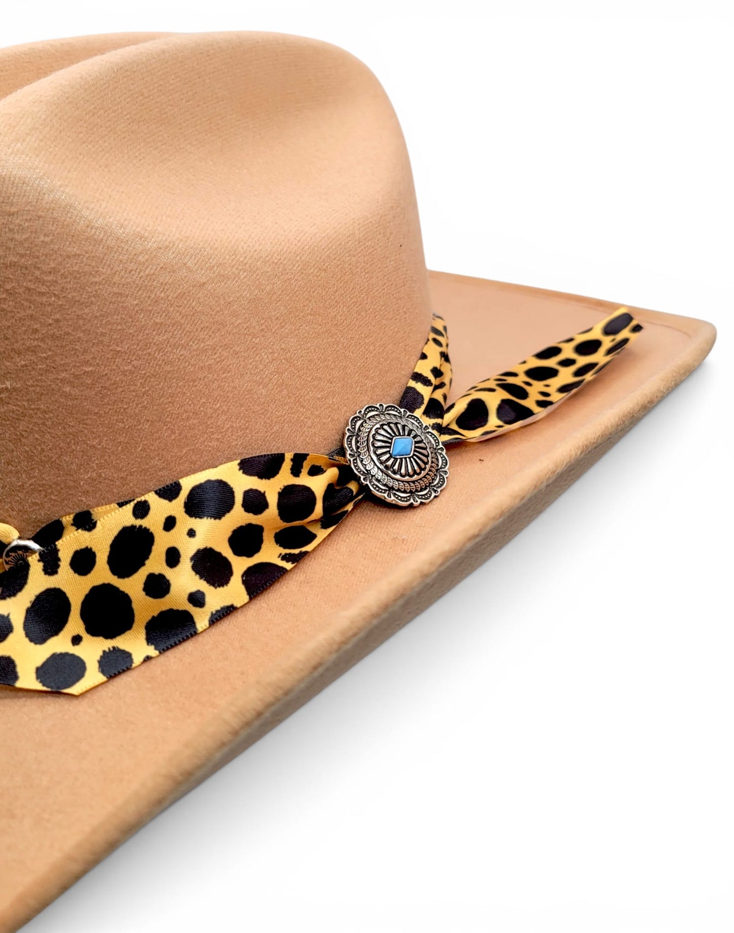 Close-up of animal-print Charlie hat band and silver-tone concho on women’s tan cowgirl hat