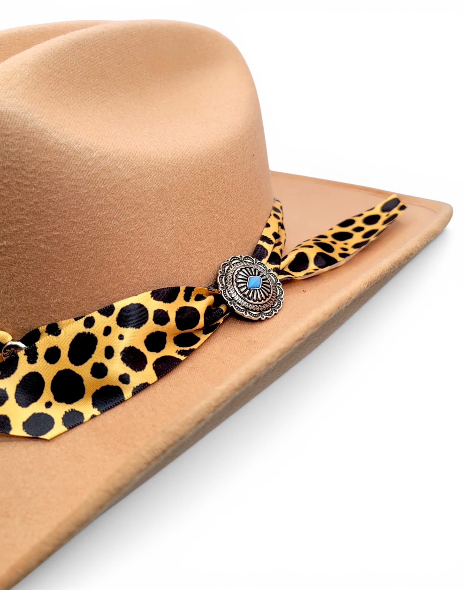 Close-up of animal-print Charlie hat band and silver-tone concho on women’s tan cowgirl hat